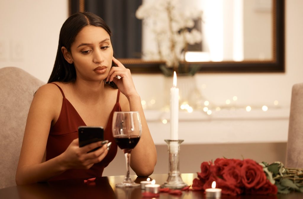 Wine, restaurant and sad woman with smartphone on date app waiting for communication. Serious, unha